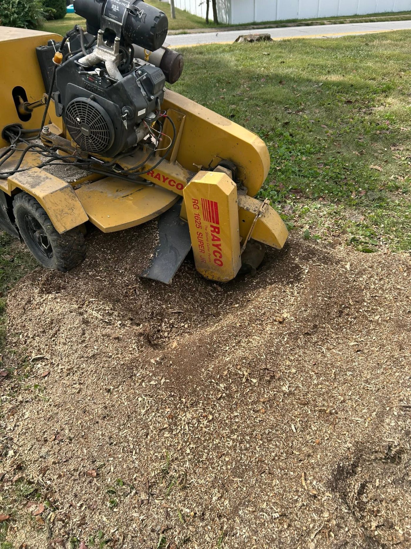 Rayco stump grinder working a freshly ground stump in a lawn