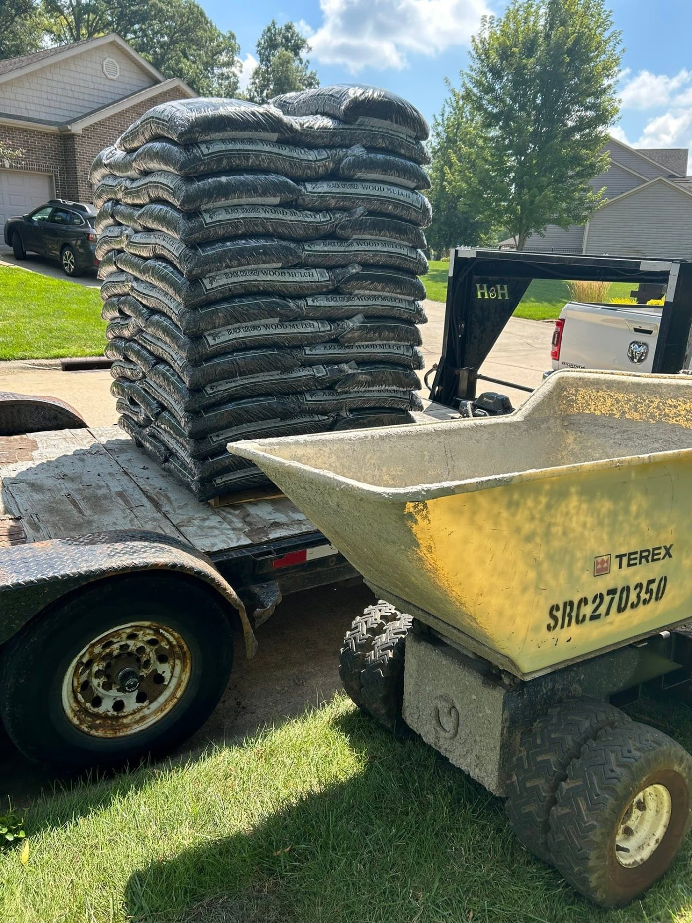 Pallet of mulch bags on a trailer beside a powered concrete buggy